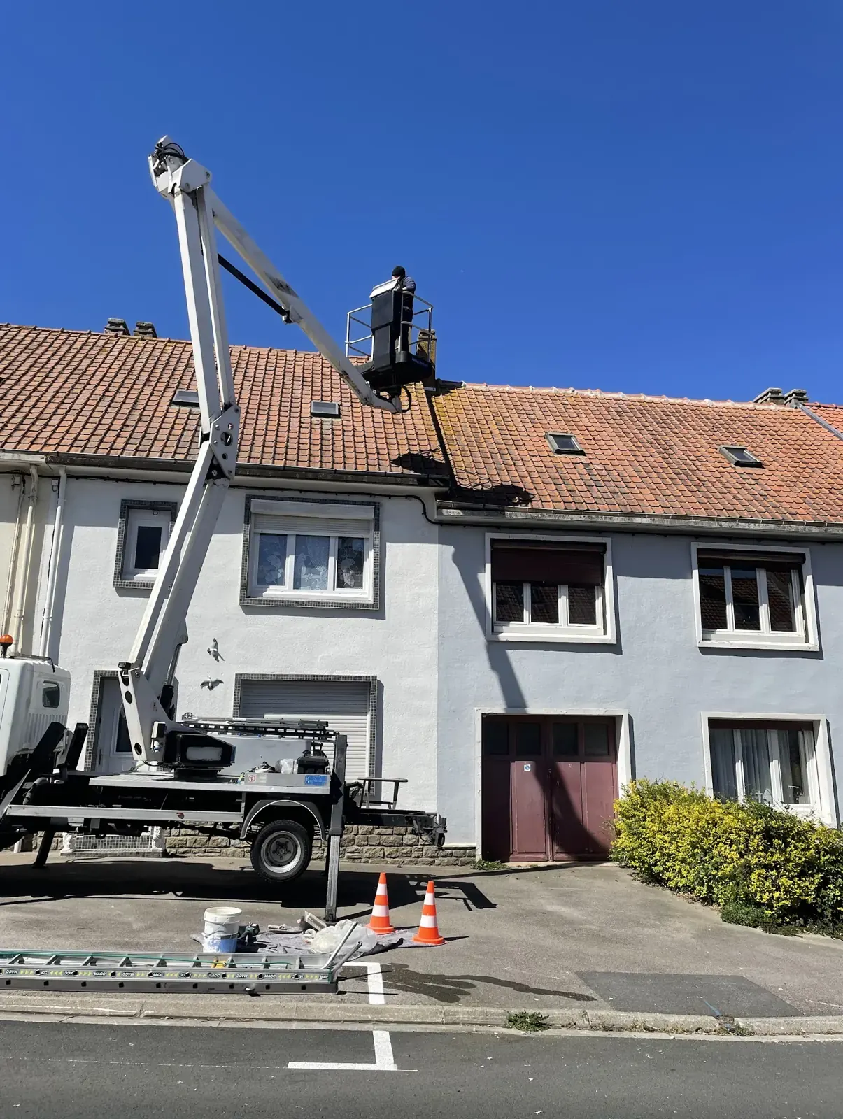 Camion nacelle de Dufresne Couverture déployé devant une maison, couvreur au travail au niveau du toit en tuiles